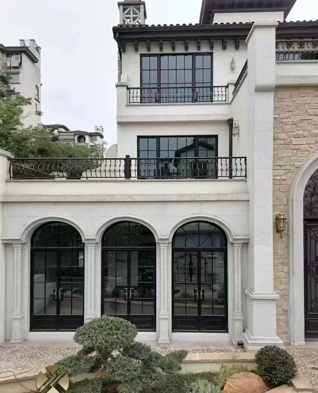 白色建筑立面上的黑色拱形玻璃门实景
